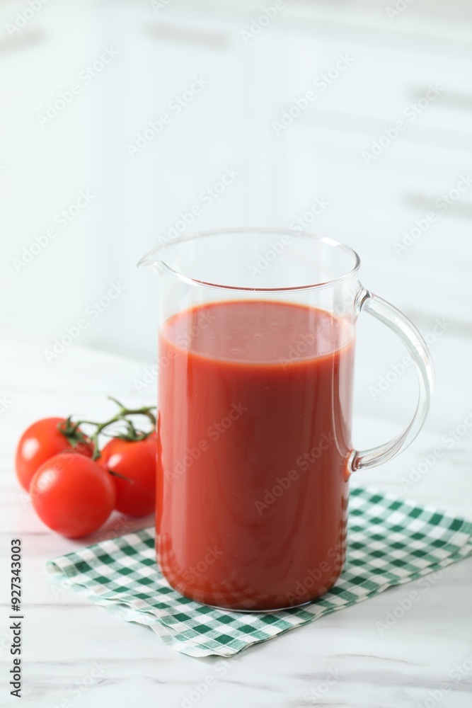Tasty tomato juice in jug and vegetables on white marble table Tasty tomato juice in jug and vegetables on white marble table