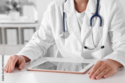 Doctor with tablet at table in clinic, closeup view