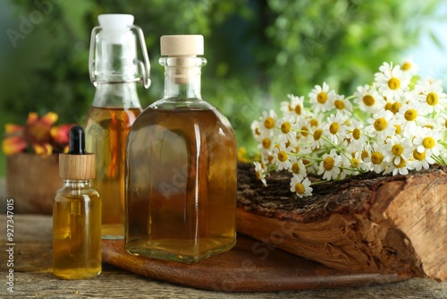 Different tinctures in bottles and chamomile flowers on wooden table