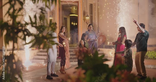 Indian Hindu Asian happy family teen girl boy child hold play crackers make fun joy night decor light diya home young adult male man female wife lady multi group older elder mom dad enjoy Diwali house