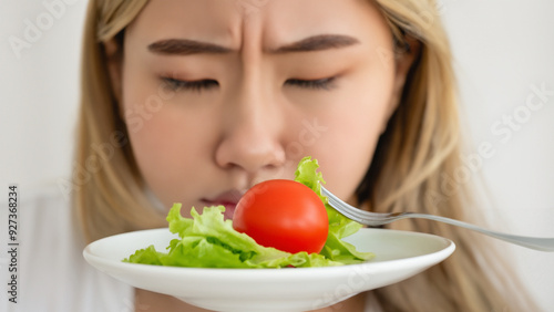 Diet bored face, unhappy beautiful asian young woman, girl on dieting tomato on salad plate, dislike or tired with eat fresh vegetables