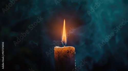 Candle aflame against dark backdrop