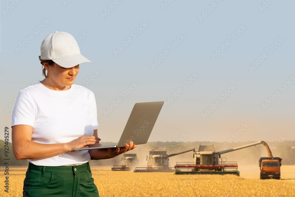 Female farmer with laptop on a background of harvesters. Smart farming concept Female farmer with laptop on a background of harvesters. Smart farming concept