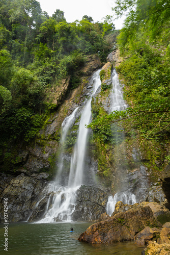 Waterfall in deep tropical rainforest with green rainy tree