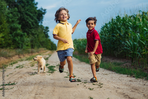 Happy Kids Running Together With Golden Retriever Puppy On Green Nature Background. Smiling Brothers. photo