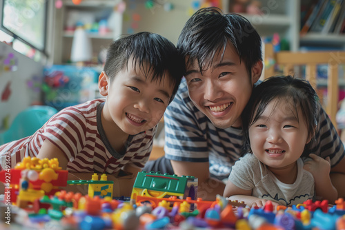 A father happily teaches his children to play with toys inside the house.