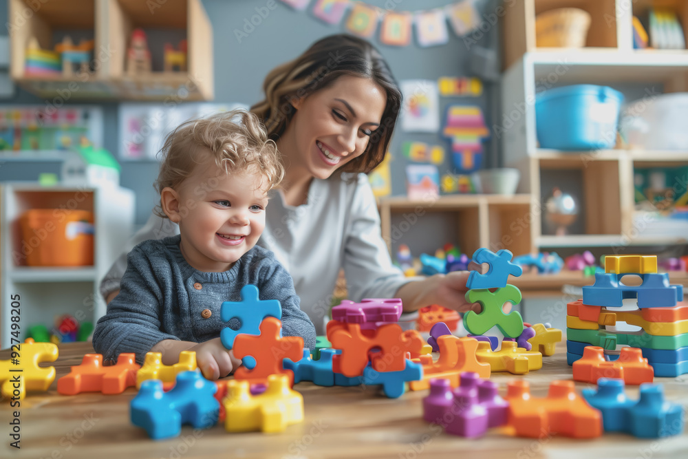Teacher and toddler playing with maths puzzle game sitting on the table at kindergarten. Teacher and toddler playing with maths puzzle game sitting on the table at kindergarten.