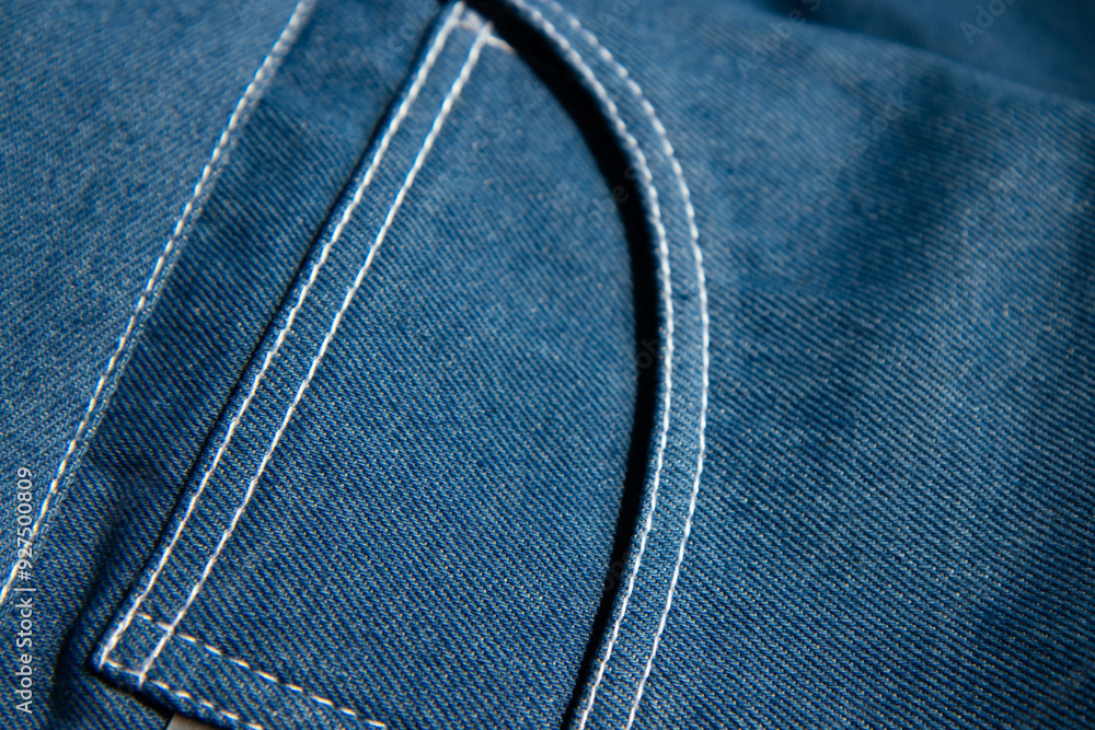 Close-up of blue denim fabric with visible stitching, capturing the texture and detail of the material.