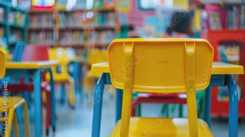 Close up of children's school chairs in the background of a blurry classroom with colorful tables and bookshelves