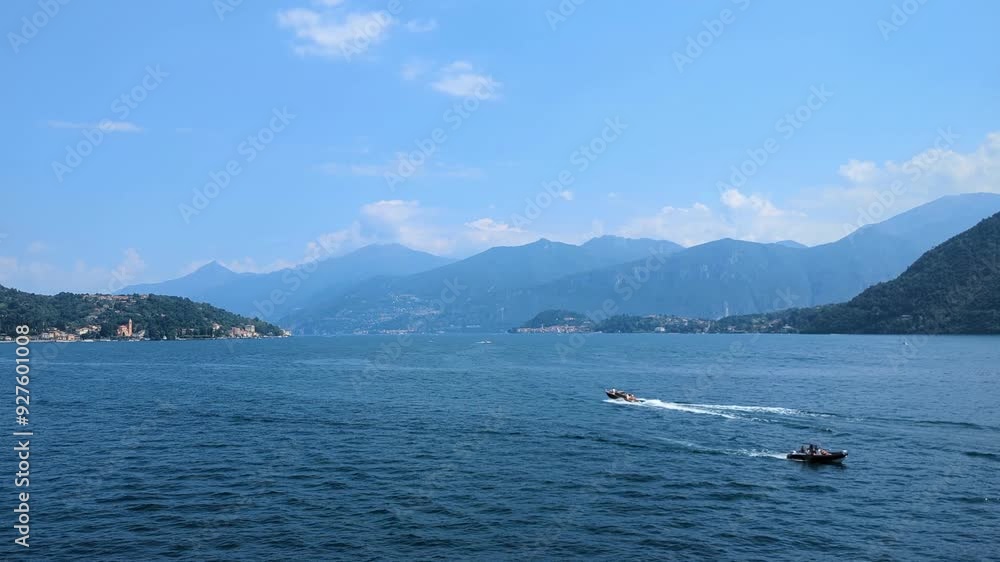 Lake Como, Bellagio. Lake side 4k stock video with two moving passenger boats passing, green forrest covered mountains, blue cloudy sky and moving blue water. Lake Como, Bellagio. Lake side 4k stock video with two moving passenger boats passing, green forrest covered mountains, blue cloudy sky and moving blue water.