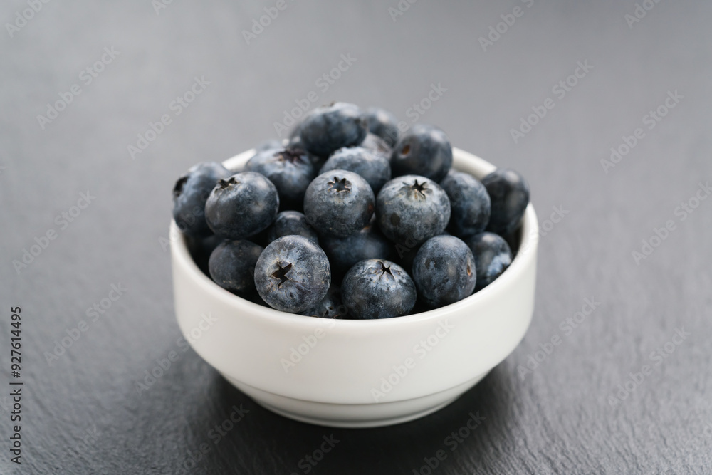 ripe blueberries in white bowl on slate background