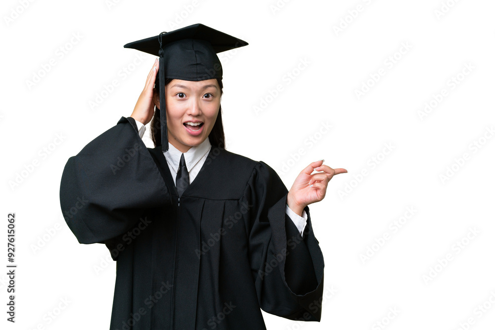 Young university graduate Asian woman over isolated background surprised and pointing finger to the side