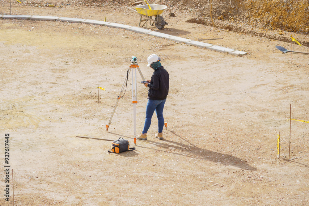 A man is standing in a field with a surveying instrument A man is standing in a field with a surveying instrument