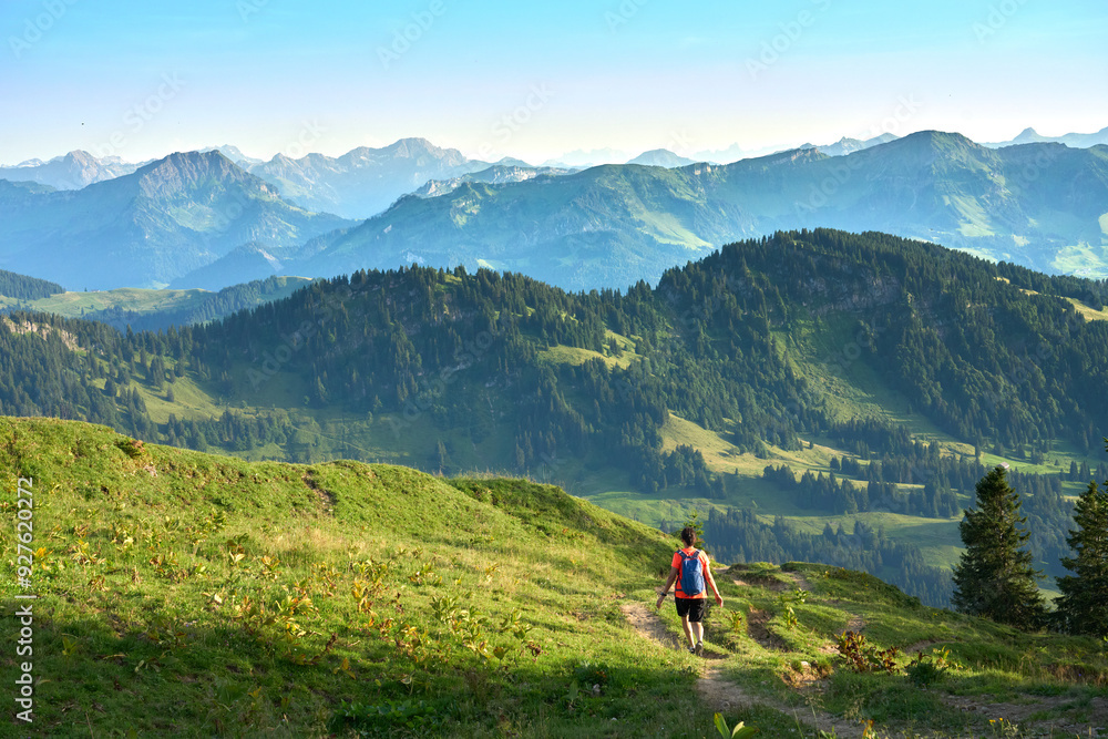 pretty senior woman hiking in warm dawn sunlight and enjoying the spectacular view over the Allgau alps on the Nagelfluh mountain chain near Oberstaufen, Bavaria, Germany pretty senior woman hiking in warm dawn sunlight and enjoying the spectacular view over the Allgau alps on the Nagelfluh mountain chain near Oberstaufen, Bavaria, Germany
