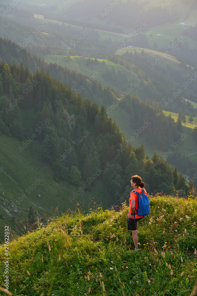 pretty senior woman hiking in warm dawn sunlight and enjoying the spectacular view over the Allgau alps on the Nagelfluh mountain chain near Oberstaufen, Bavaria, Germany pretty senior woman hiking in warm dawn sunlight and enjoying the spectacular view over the Allgau alps on the Nagelfluh mountain chain near Oberstaufen, Bavaria, Germany