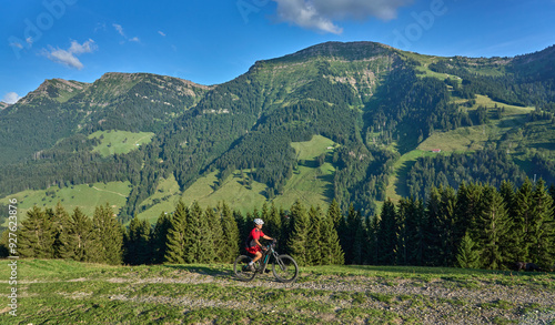 pretty senior woman riding her electric mountain bike and enjoying the spectacular view over the Allgau alps below the Nagelfluh mountain chain next to Steibis, Bavaria, Germany
 photo