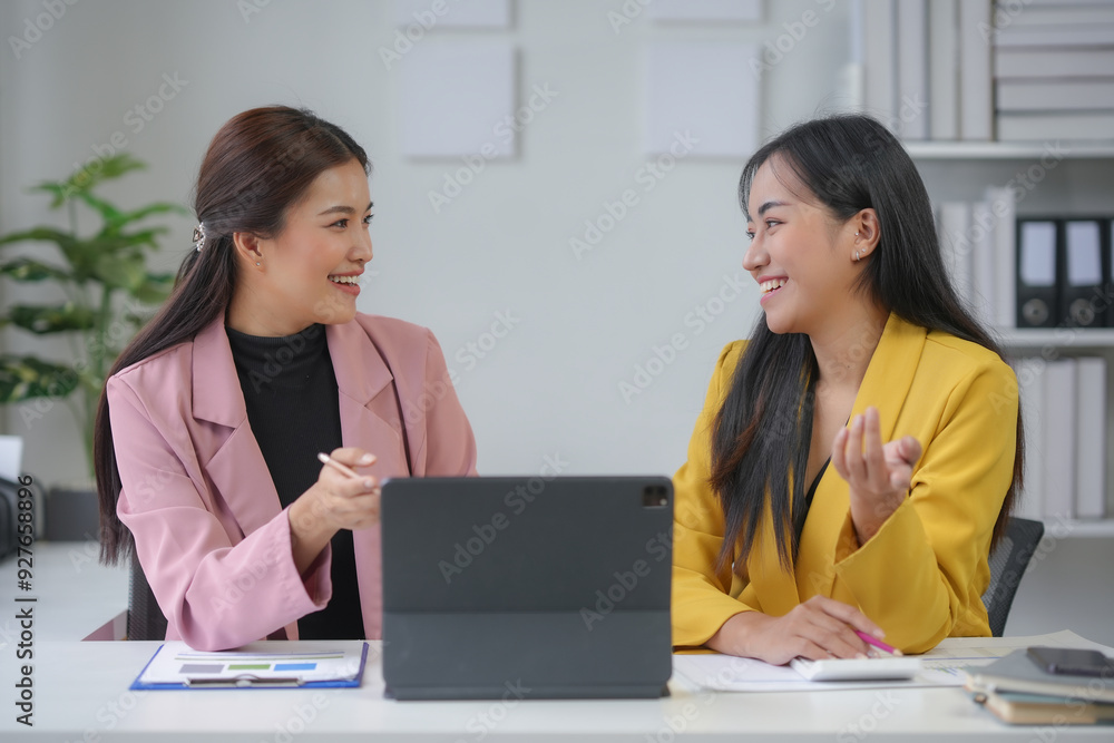 Two business women are discussing over financial reports, sharing ideas and planning new strategies for their business Two business women are discussing over financial reports, sharing ideas and planning new strategies for their business