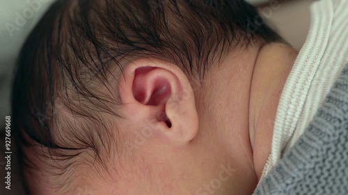 Close-up of a newborn baby's ear nestled against a blanket, showcasing the delicate features and soft skin of early infancy in a cozy, nurturing environment photo