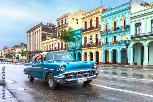 blue convertible classic car in front of colorful houses on a rainy day in havana cuba