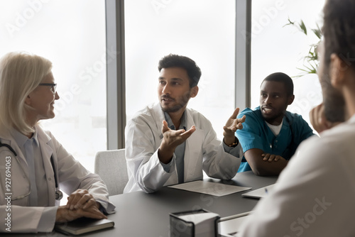 Fotografi Diverse doctors listen Indian colleague, discuss treatment option, share opinion, engaged in group decision making in modern meeting room in clinic office