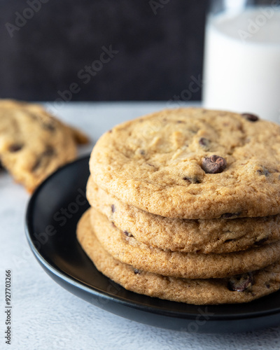 Chocolate Chip Cookies Stacked on a Plate Next to Broken Cookie and Glass of Milk