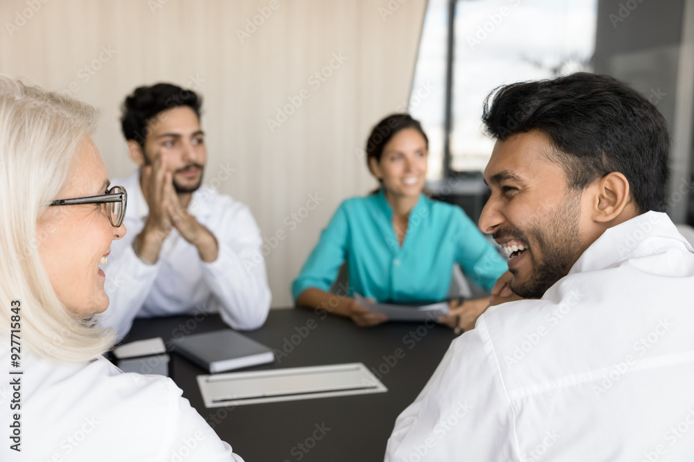 Group of doctors engaged in discussion, focus on two therapists laugh, look at each other enjoy friendly relations, positive conversation, knowledge exchange, mutual respect. Experience and internship Group of doctors engaged in discussion, focus on two therapists laugh, look at each other enjoy friendly relations, positive conversation, knowledge exchange, mutual respect. Experience and internship