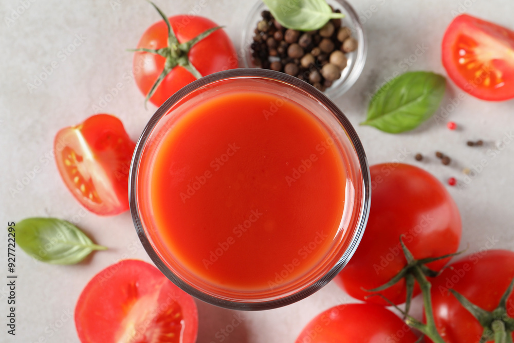 Tasty tomato juice in glass, basil leaves, peppercorns and fresh vegetables on light grey table, flat lay Tasty tomato juice in glass, basil leaves, peppercorns and fresh vegetables on light grey table, flat lay