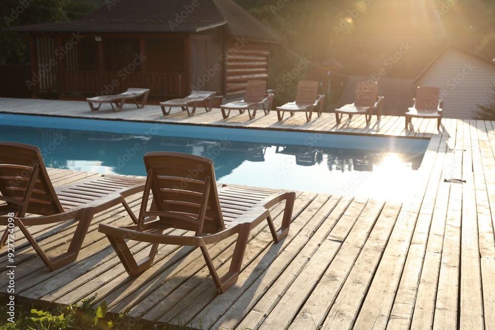 Outdoor swimming pool, sunbeds and houses on sunny day Outdoor swimming pool, sunbeds and houses on sunny day
