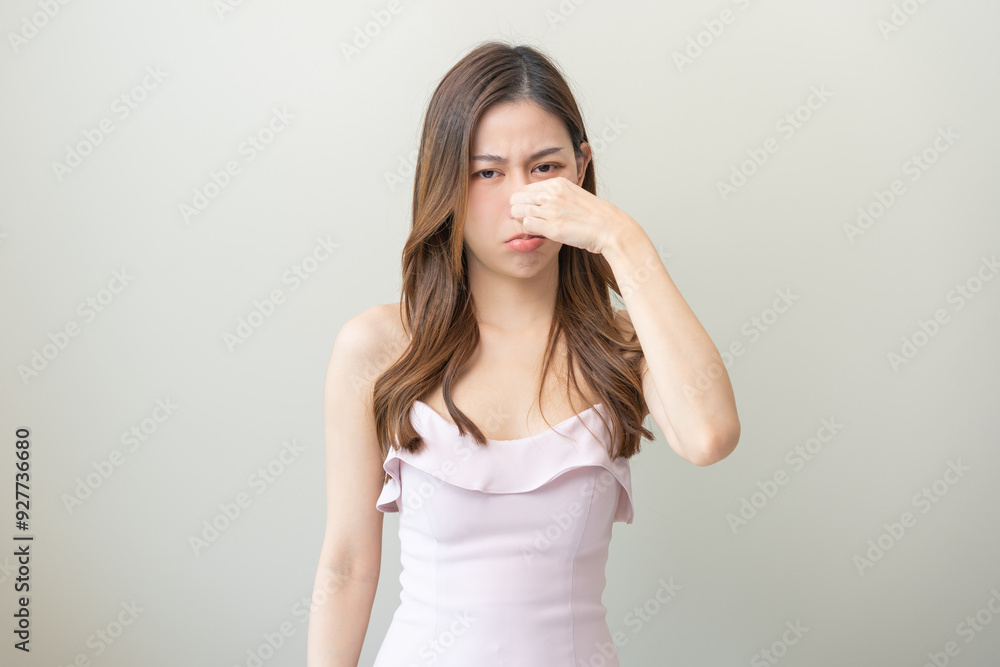 Portrait of pretty brunette hair, disgust smell bad strong asian young woman, girl hand squeezing, covering nose with fingers, expression face disgusting, dislike odor isolated on white background. Portrait of pretty brunette hair, disgust smell bad strong asian young woman, girl hand squeezing, covering nose with fingers, expression face disgusting, dislike odor isolated on white background.