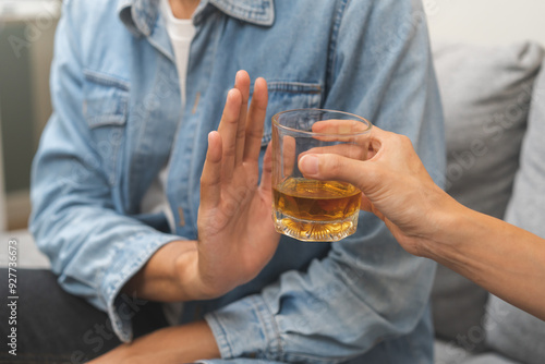 Alcoholism, depressed asian young man refuse, push out alcoholic beverage glass, drink whiskey, sitting alone at night. Treatment of alcohol addiction, having suffer abuse problem alcoholism concept.