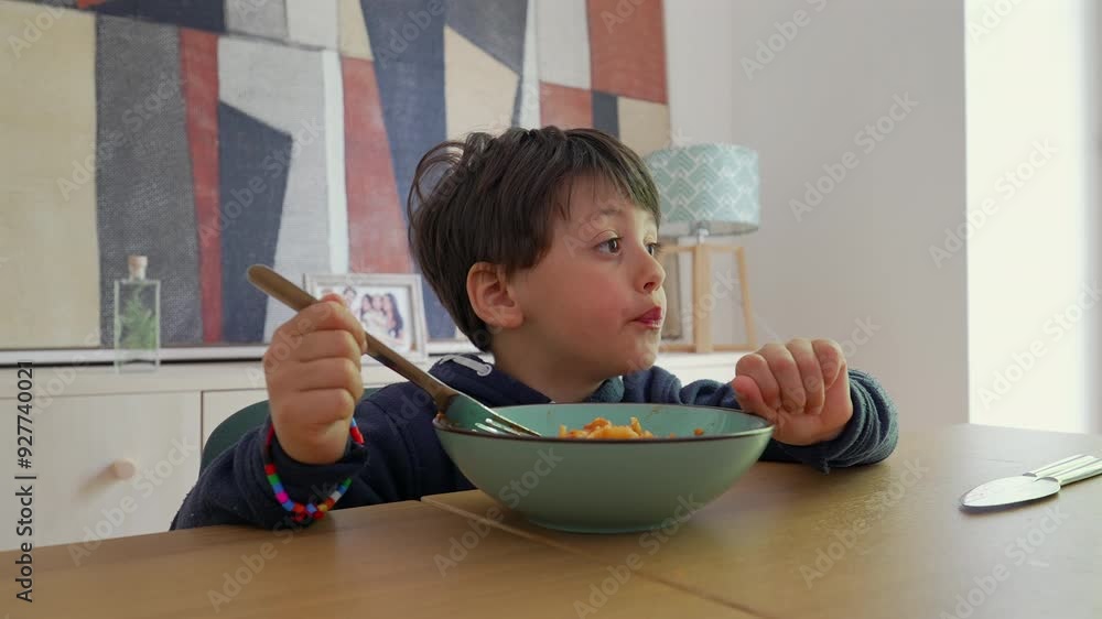 Young child intensely focused on twirling spaghetti with a fork, capturing a moment of engagement and effort during mealtime in a warm Young child intensely focused on twirling spaghetti with a fork, capturing a moment of engagement and effort during mealtime in a warm