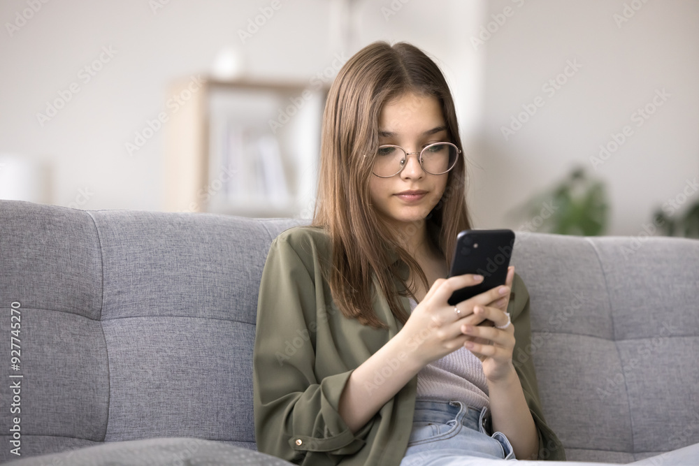 Serious teenager girl using cellphone at home, watching videos on streaming movies and TV platforms, playing mobile games, chatting with friends through messenger. Modern gadgets overuse, bad habit Serious teenager girl using cellphone at home, watching videos on streaming movies and TV platforms, playing mobile games, chatting with friends through messenger. Modern gadgets overuse, bad habit