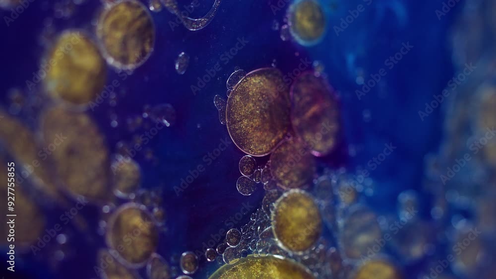 Glitter oil drops. Paint flow. Sparkling emulsion. Wet gloss. Defocused blue indigo purple golden yellow color shimmering particles blobs ink water fluid motion abstract art background. Glitter oil drops. Paint flow. Sparkling emulsion. Wet gloss. Defocused blue indigo purple golden yellow color shimmering particles blobs ink water fluid motion abstract art background.