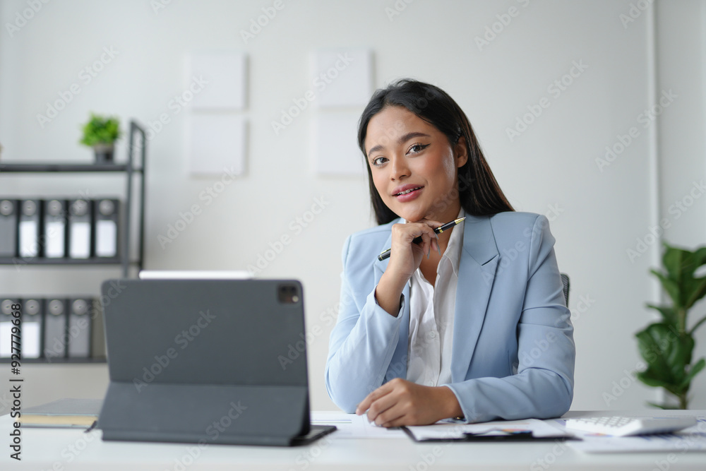 Young manager woman is smiling while sitting at her desk in her workplace office Young manager woman is smiling while sitting at her desk in her workplace office
