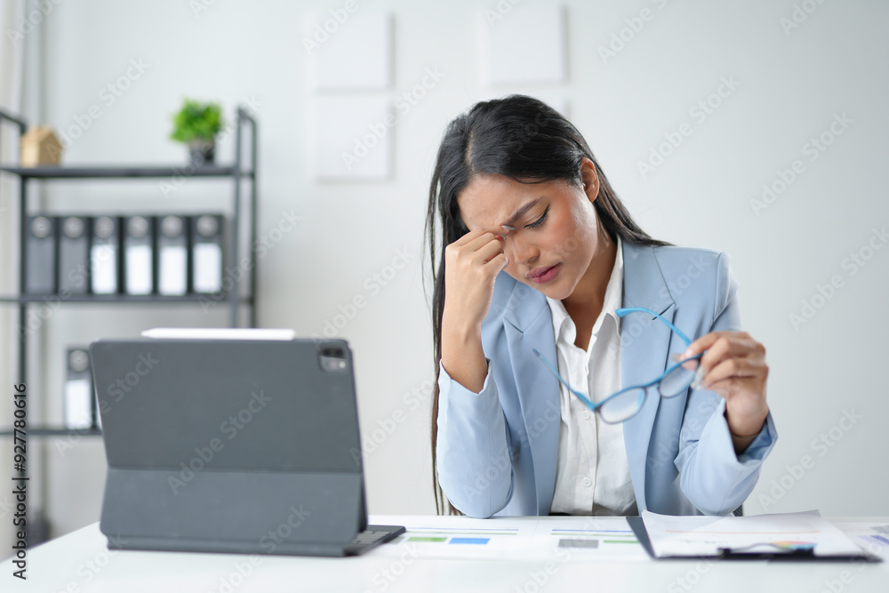 Young asian businesswoman having a headache and feeling tired from working on a laptop for a long time Young asian businesswoman having a headache and feeling tired from working on a laptop for a long time