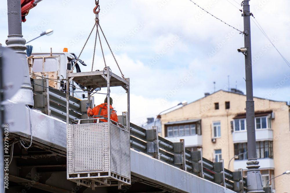 worker is suspended in a metal basket, hoisted by a crane to repair a bridge. This scene embodies the blend of human skill, engineering, and the risk inherent in construction work worker is suspended in a metal basket, hoisted by a crane to repair a bridge. This scene embodies the blend of human skill, engineering, and the risk inherent in construction work