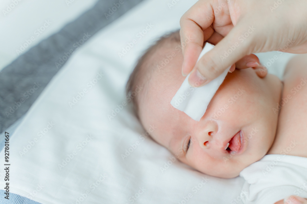 Mother cleans newborn's eyes with cotton and saline solution. Mother cleans newborn's eyes with cotton and saline solution.