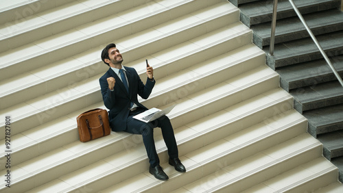 Top view business man celebrate successful project while sitting at stairs. Smart project manager getting new job, getting promotion, increasing sales while calling friends by using phone. Exultant.