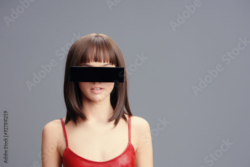 A woman in a red dress, blindfolded, stands against a gray background, capturing a sense of mystery and elegance