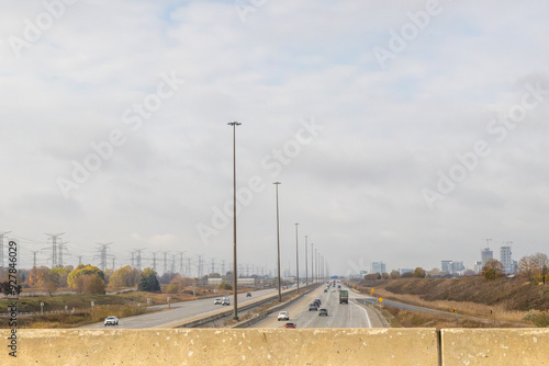 Photography Overcast sky above a bustling highway, flanked by power lines and buildings - vehicles in motion