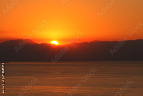 sunset or sunrise over the sea behind the mountain