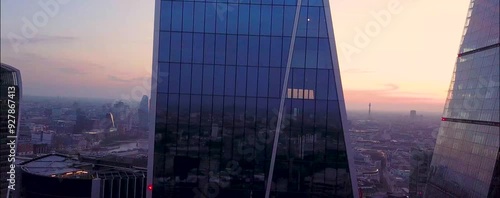 
As the sun begins to set over London, the city's iconic skyline is bathed in a warm, golden glow. From a drone's aerial perspective, the skyscrapers rise majestically, their glass facades reflecting 