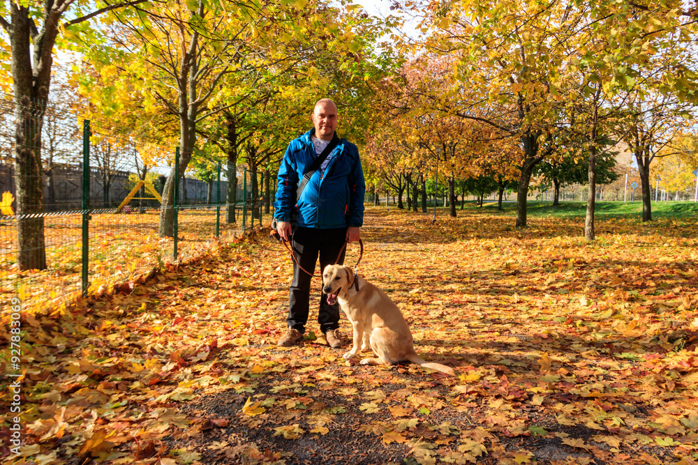 Handsome man walking his labrador retriever dog in autumn park Handsome man walking his labrador retriever dog in autumn park