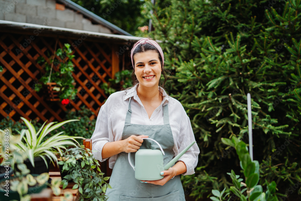 Young woman taking care of plants with water can and mister in garden Young woman taking care of plants with water can and mister in garden