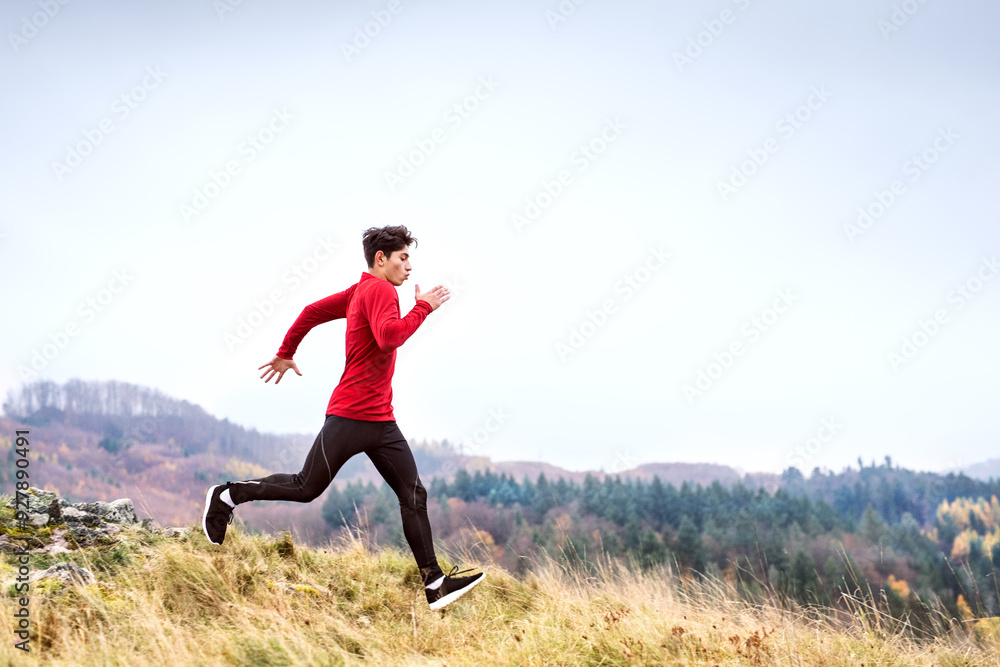 Male runner jogging in nature on dirt running trail. Morning running training for young man. Male runner jogging in nature on dirt running trail. Morning running training for young man.
