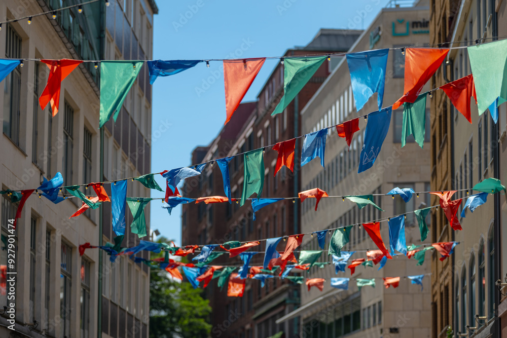 Obraz premium Colourful flags above a shopping street in summer.