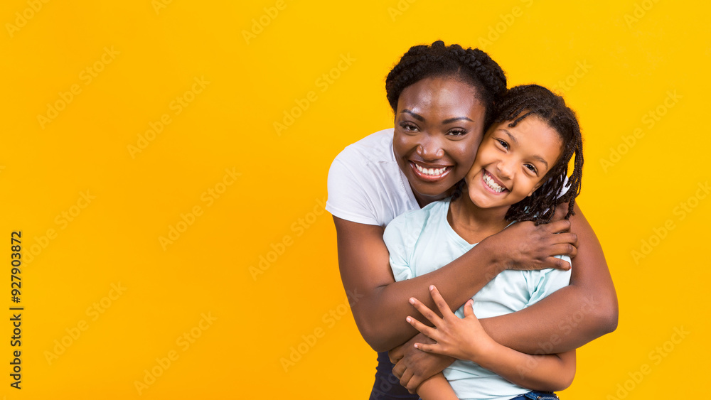 Black Mom Embracing Her Daughter, Looking Happy And Overjoyed. Yellow studio background, copy space Black Mom Embracing Her Daughter, Looking Happy And Overjoyed. Yellow studio background, copy space