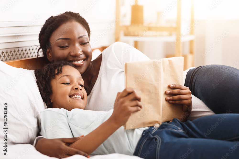 Bedtime Story. Happy black mom and her child reading book together, lying in bed at home, copy space Bedtime Story. Happy black mom and her child reading book together, lying in bed at home, copy space