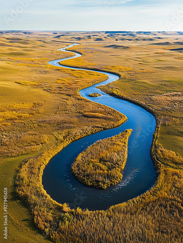 Aerial view of winding river through golden fields in expansive landscape.
 photo