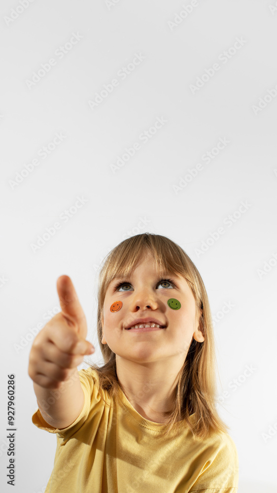Excited little girl with emojis on face shows thumbs up. Copy space Excited little girl with emojis on face shows thumbs up. Copy space